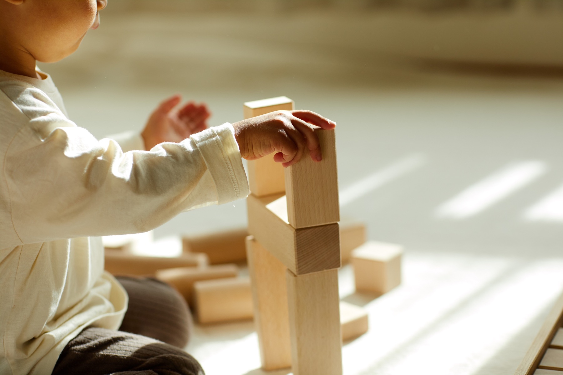 木の積み木を重ねる子どもの手元